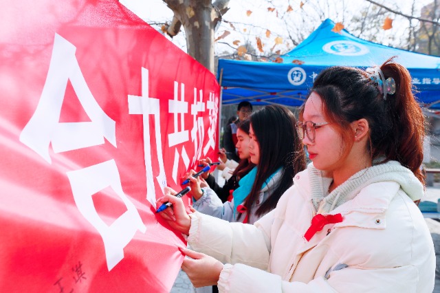 20231127中國石油大學(xué)（華東）青年學(xué)子在合力共抗艾滋的條幅上簽字，表達(dá)抗擊艾滋病的決心和信心  .jpg