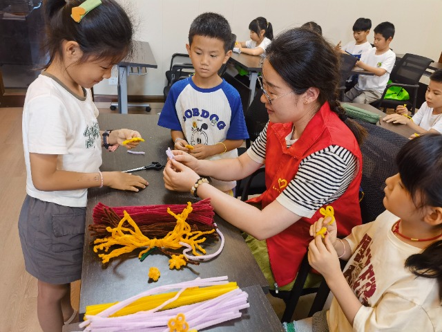 7月12日，在泰州市海陵區(qū)城東街道林湖社區(qū)，泰州市大浦小學(xué)“綠葉”暑期公益班的老師正在教孩子們一起做手工2（拍攝者：泰州市大浦中心小學(xué)  陳惠婷）.jpg