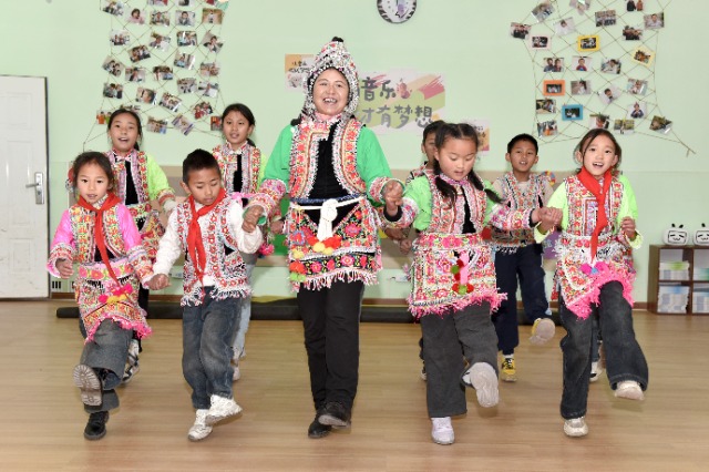 馬游小學(xué)社團(tuán)課上，梅葛文化國(guó)家級(jí)傳承人羅英老師教學(xué)生邊唱娃娃梅葛調(diào)邊跳彝族舞蹈。（蔡興華  攝影）.JPG